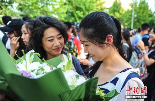 資料圖：山東濟(jì)南眾多考生手捧鮮花在家長(zhǎng)的簇?fù)硐職g快告別高考。中新社記者 張勇 攝