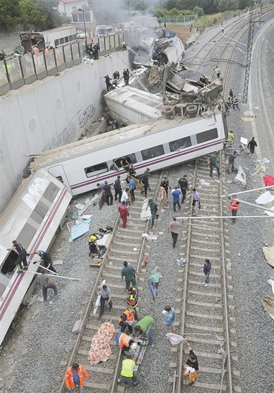 24日，救援人員在西班牙列車脫軌現(xiàn)場。一節(jié)車廂被強(qiáng)大的慣性拋上鐵道邊的高臺。