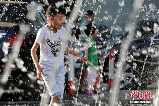 山西太原最高溫36℃,兒童在噴泉周圍戲水消暑。