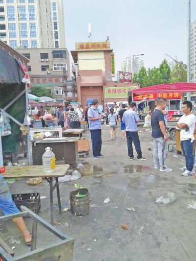 昨天，執(zhí)法人員在京廣路長江路口整治“僵尸圍擋”及圍擋內(nèi)的攤販。