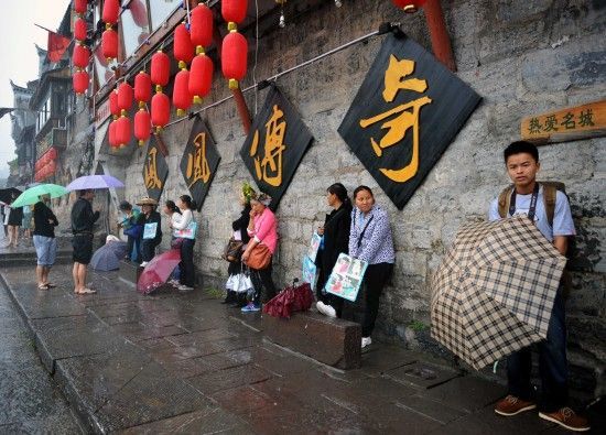 　4月29日上午11時(shí)20分，一些游客和古城當(dāng)?shù)氐木用穸阍谝粋€(gè)酒吧的屋檐下避雨。這些當(dāng)?shù)鼐用褚詾橛慰团恼罩\生，一場(chǎng)降雨讓他們的生意更加清淡。