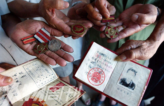 幾位志愿軍老兵展示自己的立功證、傷殘軍人證與勛章