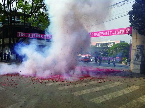 市民在普洱市主干道振興大道的金孔雀交通運(yùn)輸集團(tuán)有限公司門前燃放鞭炮，公司門前掛著“貪腐份子沈培平被查處，罪有應(yīng)得，大快人心。”的條幅