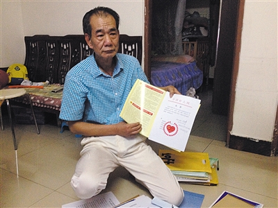 翻出一家網(wǎng)站贈予的“中國好人”證書，區(qū)少坤單膝跪在地上，“你看，我是中國好人啊?！?范春旭 攝