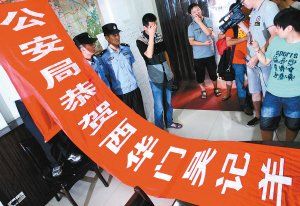 面對(duì)警方收繳的條幅，老板楊某也不好意思地用手遮擋臉