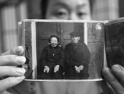 圖為孫女拿出兩位老人上世紀(jì)80年代在家門口的合影給記者看。記者楊濤 攝