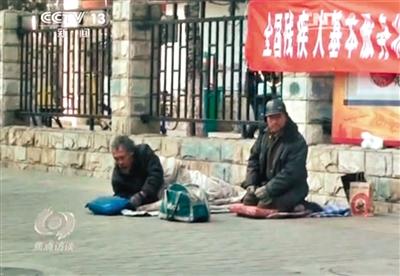 工人體育場(chǎng)北路，兩位乞討者路邊乞討，并輪流扮成“病人”（躺地者）。 央視截圖