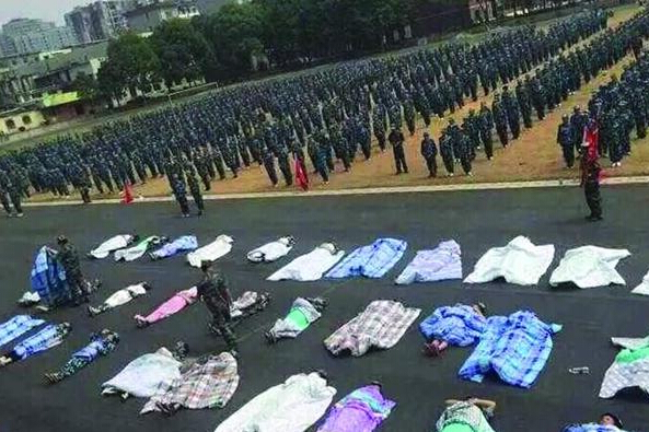 20多名女生躺在瀝青跑道上，身上嚴(yán)嚴(yán)實(shí)實(shí)地裹著棉被，接受太陽(yáng)的照曬。