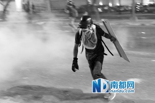 反政府示威者在與警察的沖突中躲避催淚彈。