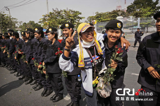2013年12月03日,曼谷總理府與曼谷警署允許反政府示威民眾進(jìn)入,雙方進(jìn)入暫時(shí)“停戰(zhàn)”狀態(tài)迎接泰王生日。曼谷警察總署,女警們手持鮮花送給反政府示威民眾。圖片來(lái)源:Manish Swarup/東方IC