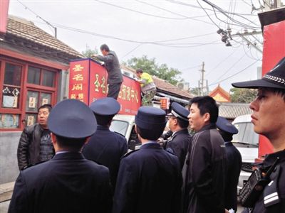 昨日下午,東城區(qū)工商、城管、公安等部門,對雍和宮附近的預(yù)測中心進行清理整頓,站在車頂?shù)膬擅と苏鸪患摇邦A(yù)測中心”的招牌。因雍和宮、白云觀等文化景點外聚集大量算命先生,被媒體稱為“算命一條街”。本版攝影/新京報記者 李寧 攝