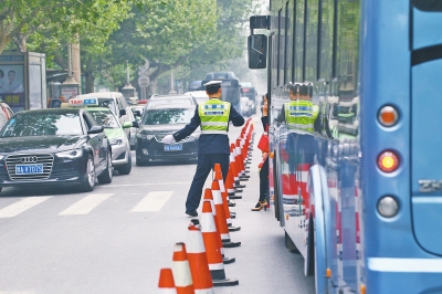 省人民醫(yī)院南門的路中間擺放反光錐，交警示意由西向東車輛從前方繞行。