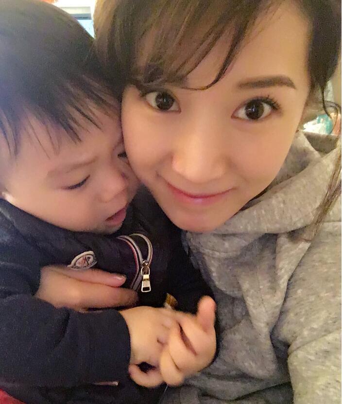 照片中李念狂吻兒子，小寶貝自顧自地玩著。