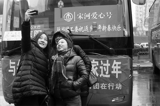 昨天上午8時，鄭州正道中環(huán)百貨廣場，準(zhǔn)備回家的老鄉(xiāng)在愛心大巴車前合影留念