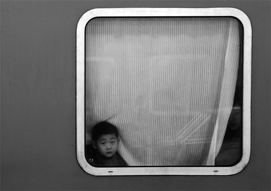 一個(gè)孩子把頭伸向窗外，他想再看送別的親人一眼