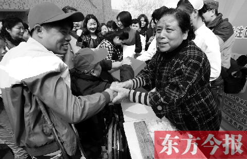 昨日，鄭大四附院的大樓前，“面人鄭”鄭玉芬（右）向前來捐款的殘疾人表示感謝