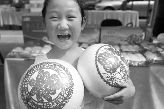 在2013河南食品安全宣傳周活動(dòng)現(xiàn)場(chǎng)，一個(gè)小女孩抱著參展的特色大饅頭樂開了花