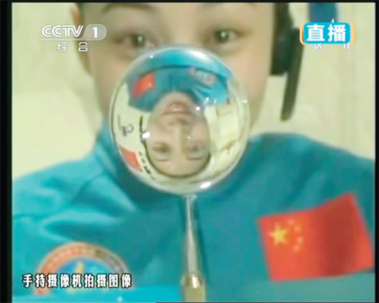 王亞平的倒影出現(xiàn)在水球中。新華社發(fā)（視頻截圖）