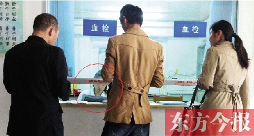昨日，鄭州市二七區(qū)疾控中心辦證大廳，血檢窗口內(nèi)一名女工作人員，邊接受辦證者咨詢邊看報(bào)紙
