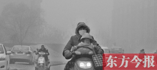 12月8日，鄭州市未來路上，一位市民帶著孩子在霧中騎行