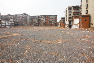 為降塵，旮旯王村拆遷后裸露的地面上鋪了一層石子。
