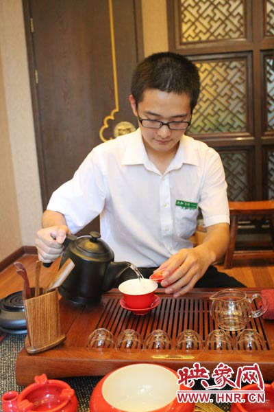 1、水壺里的水煮沸，李克勤把茶葉放進茶荷里，準備溫杯沖茶