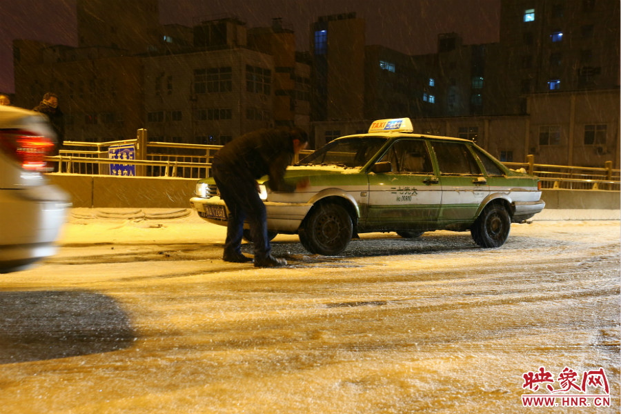 一位出租車司機(jī)在車輪前灑上雪，希望能增加輪胎的摩擦力。