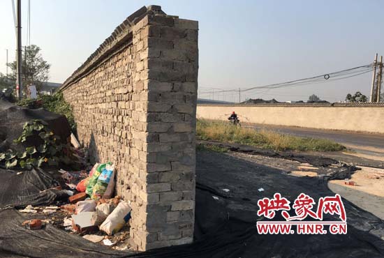 一墻之隔，一邊是道路，一邊是垃圾和荒草，市民質(zhì)疑其為遮羞墻。