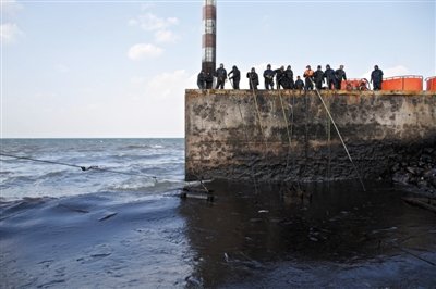 昨日，山東青島，清污人員正在海邊清理油污。