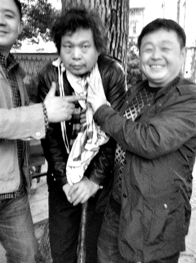 兩名接訪人員與患有癌癥的訪民段新德合影時(shí)，面帶笑容擺出勝利的手勢(shì)。