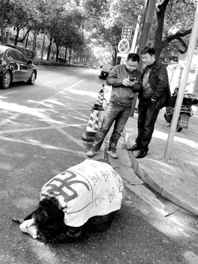 兩名接訪人員與患有癌癥的訪民段新德合影時(shí)，在拍照時(shí)查看手機(jī)。