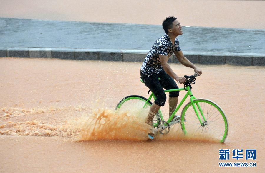 5月11日，一名行人在深圳街頭冒雨騎行。