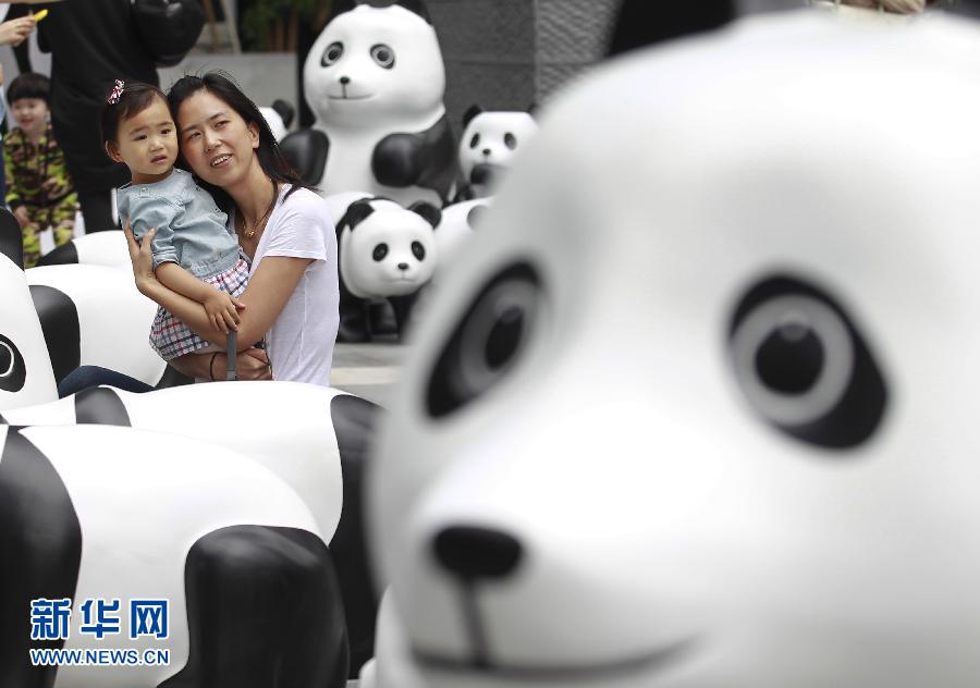 6月2日，一位家長(zhǎng)帶著孩子在上海街頭和大熊貓模型合影。