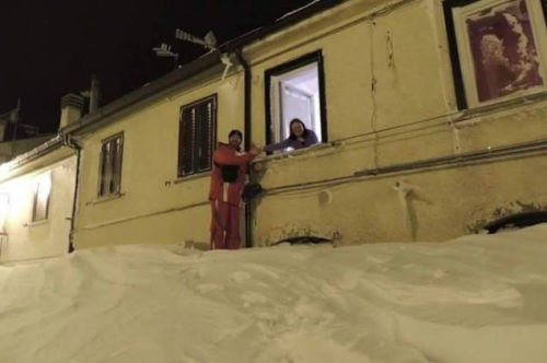 一個居民站在積雪上，可以與一名二樓鄰居在窗口握手。（來源：意大利氣象局）