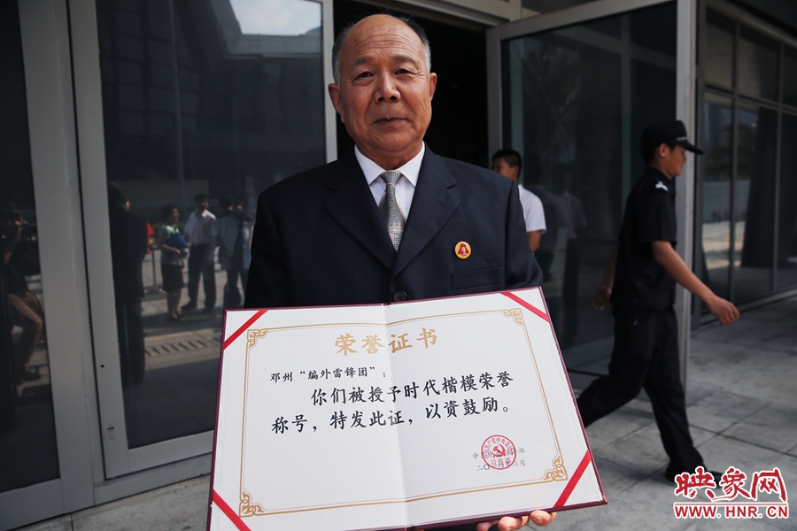 河南鄧州“編外雷鋒團”團長宋清梅向眾多記者展示中宣部授予的“時代楷?！睒s譽證書。