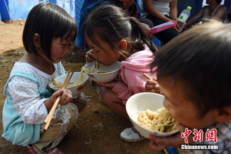 2014年8月6日，云南魯?shù)辇堫^山災(zāi)區(qū)，兒童在帳篷外吃飯。