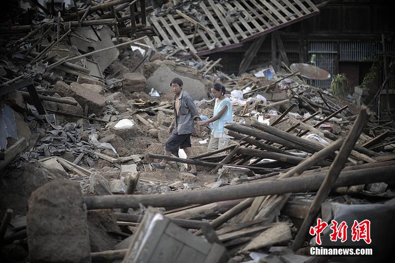 2014年8月5日，云南昭通龍頭山鎮(zhèn)老街，一對夫妻從居住房屋的廢墟中走過。