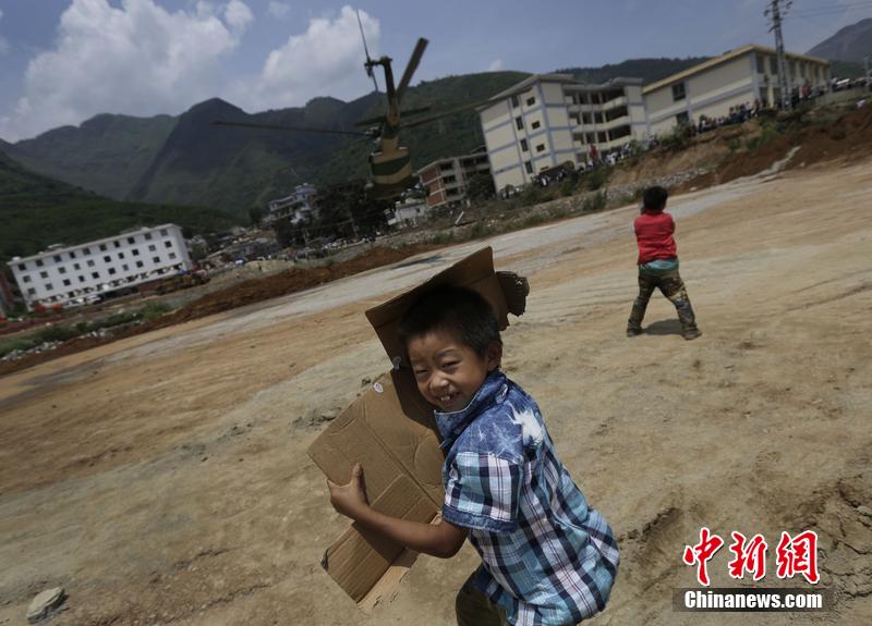 云南省昭通市魯?shù)榭h發(fā)生6.5級地震。幾個孩子在直升機降落的平地上玩耍。