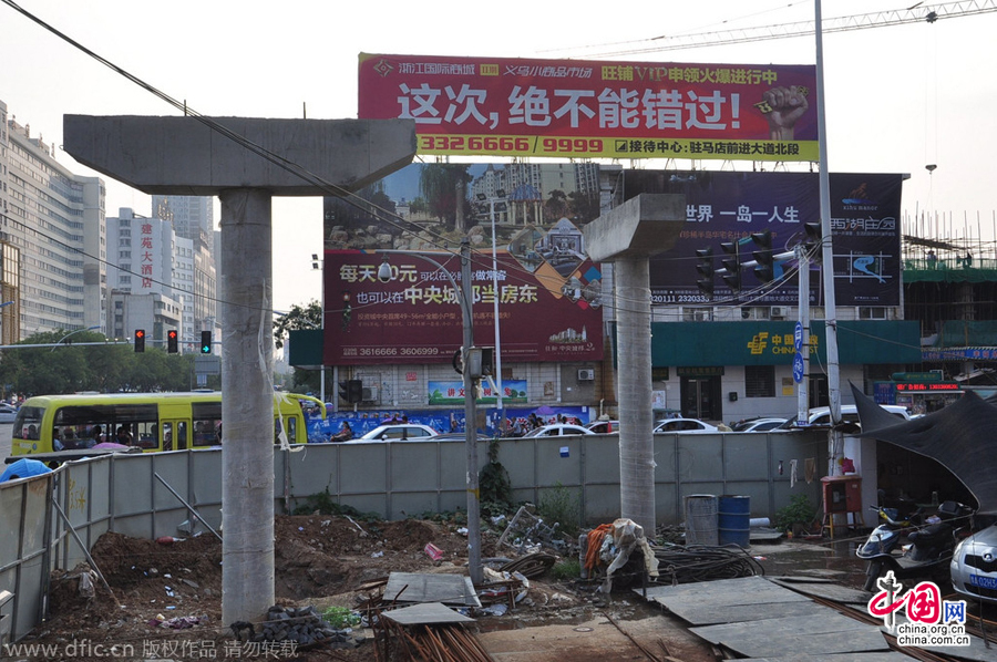 過街天橋一側(cè)的橋樁早已打好,可是對(duì)面的郵政銀行網(wǎng)點(diǎn)依舊在照常營(yíng)業(yè)。