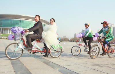 氣球和鮮花裝點(diǎn)的雙人自行車，新郎郝幸福載著美麗新娘回家。