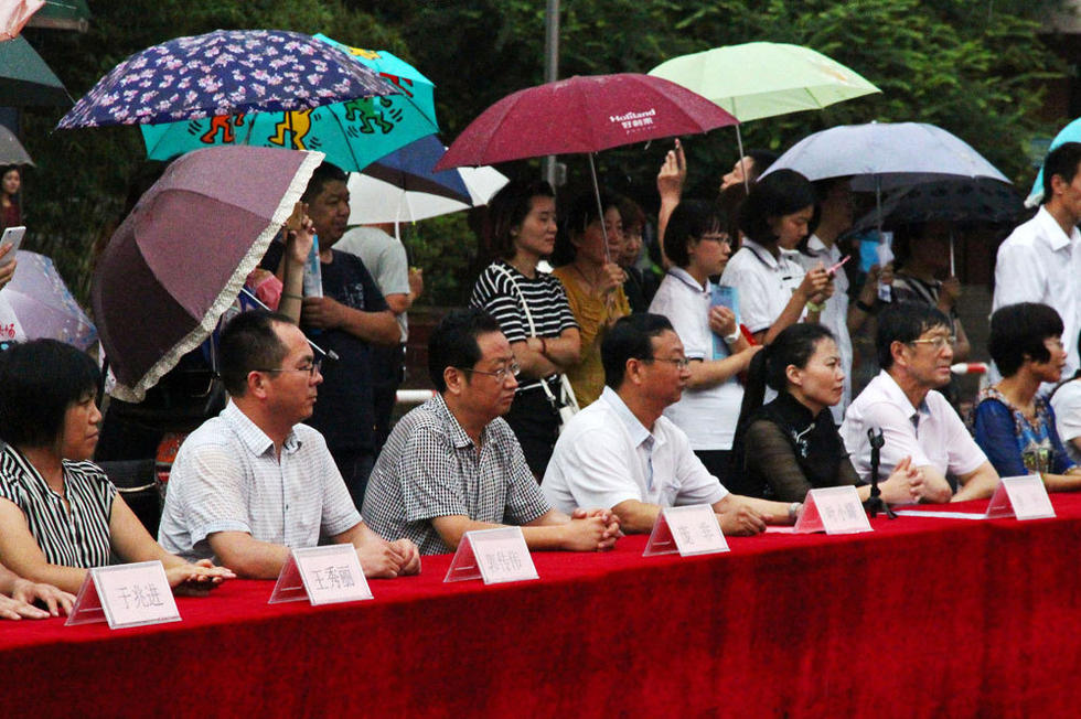 在主席臺上觀看的校領導也堅持不打傘陪學生一起淋雨，身旁站滿了打傘觀看的家長。