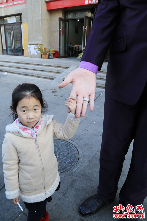 巨人“張歡”牽著一名漂亮的小女孩，兩人的手大小對(duì)比非常明顯。