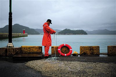 7月6日，韓國珍島，一名海岸警察在港口系救生圈。4月，客輪在珍島近海發(fā)生沉船事故后，仍有11人下落不明。