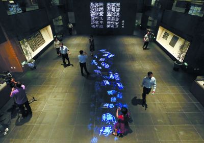 昨天，在國(guó)家典籍博物館內(nèi)，通過藝術(shù)投影技術(shù)呈現(xiàn)在展廳地面上的“漢字歷史長(zhǎng)河”，引得參觀者駐足觀看。