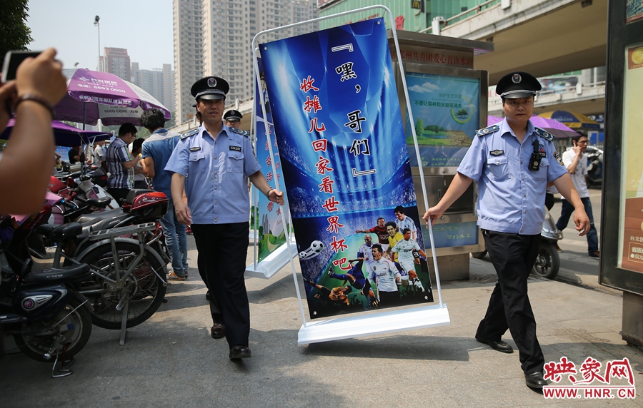 7月2日上午，鄭州市紫荊山地鐵站出入口，執(zhí)法人員抬著寫有勸導(dǎo)語的宣傳板，前往占道經(jīng)營攤位“圍觀執(zhí)法”